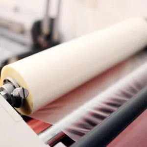 Close-up van de wals van een lamineermachine die een dunne plastic verpakkingsfolie bewerkt.
