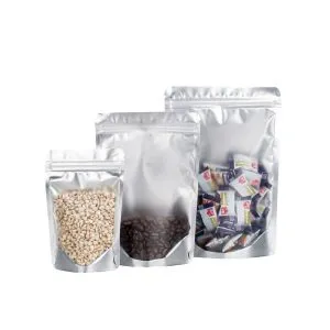 Três sacos Mylar stand up prateados da KanzoPack de tamanhos variados preenchidos com grãos, grãos de café e balas embaladas.