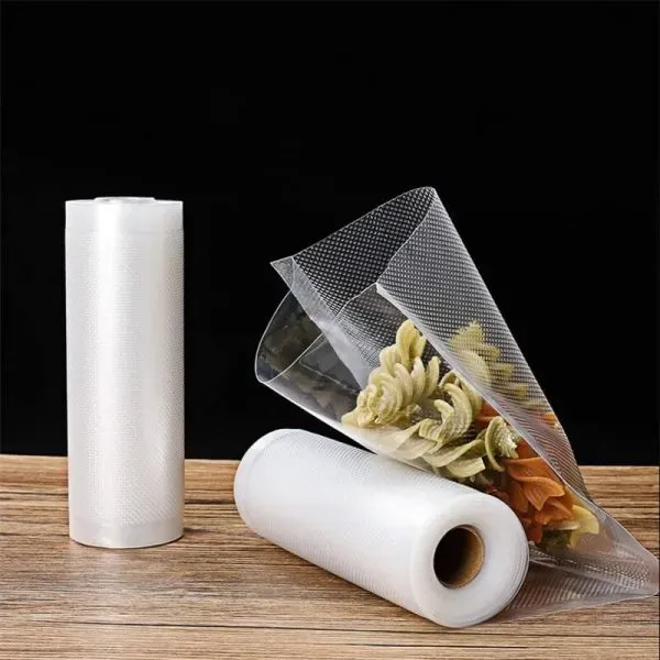 Rollos de bolsa para envasado al vacío de alimentos de KanzoPack y una bolsa llena de pasta sobre una mesa de madera.
