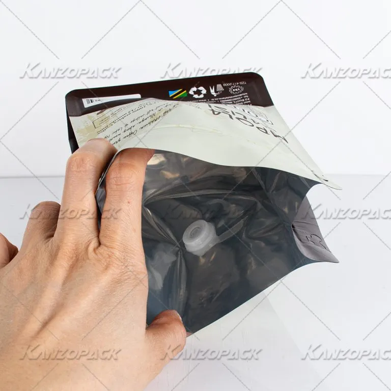 Una mano sosteniendo abierta una bolsa de café KanzoPack para mostrar el revestimiento interior y la válvula.
